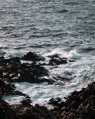 黑色岩石海岸，白天海浪拍打岩石